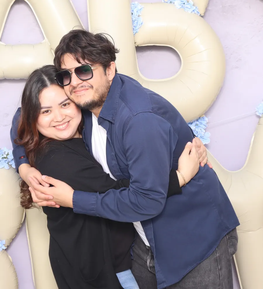 A couple hugging in front of giant balloon letters spelling baby