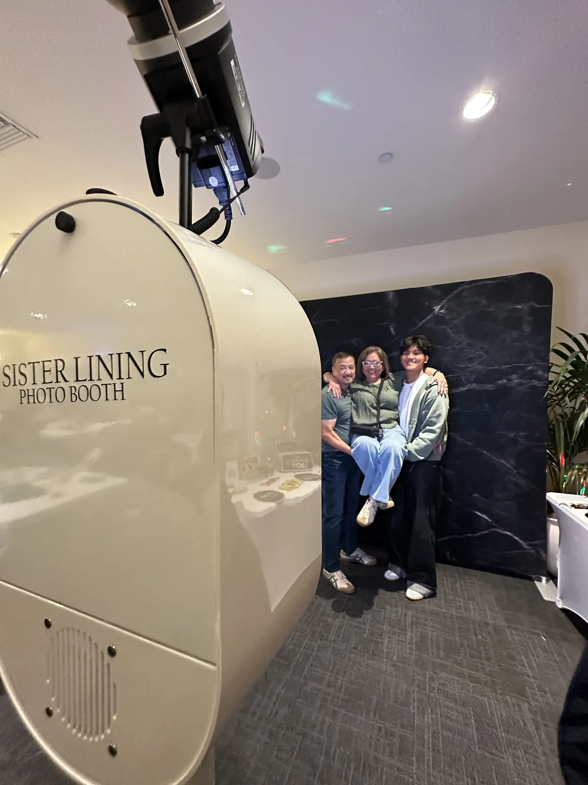 The Sister Lining booth set up at an event with guests posing beside it
