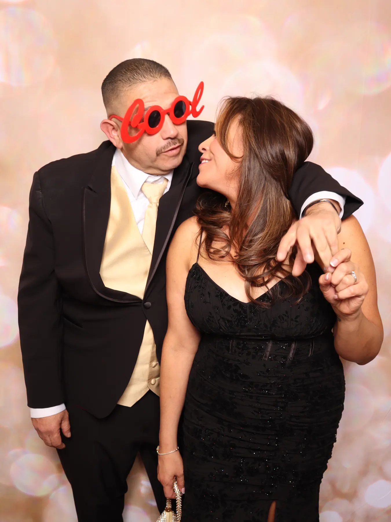 A couple laughing with a prop in front of the blush backdrop