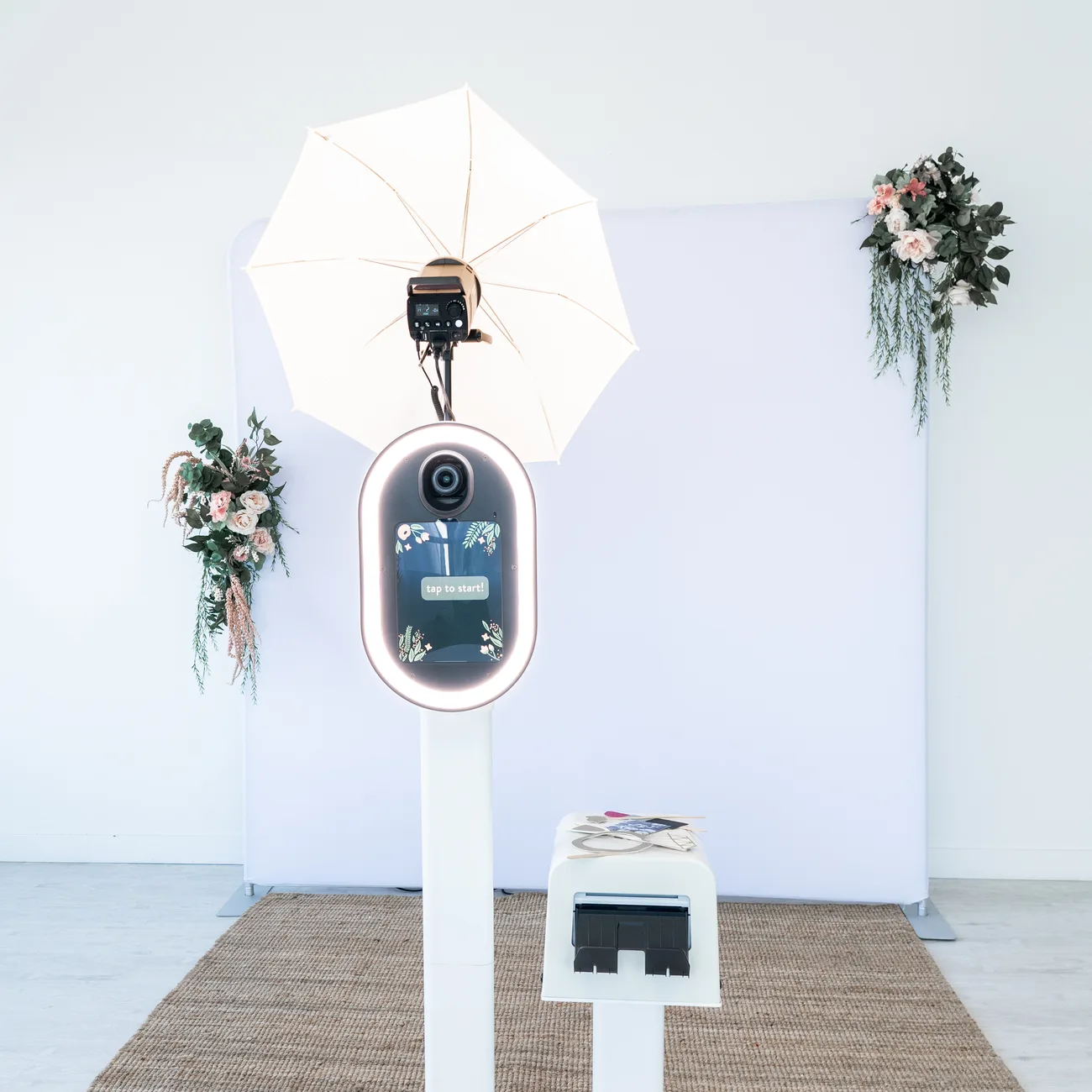 The booth set up with a floral backdrop and umbrella light before an event